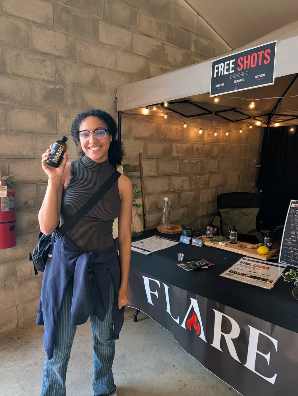 A woman in round glasses raises a bottle of Flare beside the black Flare banner.