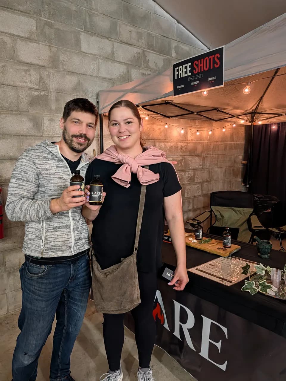 A man and a woman each hold up a bottle of Flare under the free shots sign.